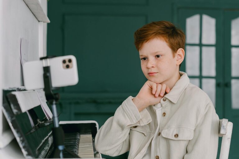 A focused young boy takes piano lessons online, showcasing the blend of education and music at home.